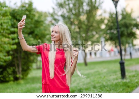 Beautiful woman in red dress makes selfie
