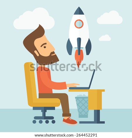 An enthusiastic, eager hipster Caucasian young man with beard sitting in front of his laptop browsing, researching  and planning a metaphor for new business. On-line start up business concept. A