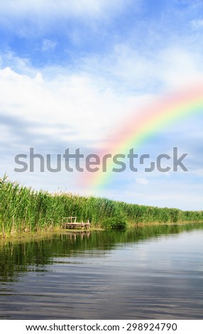 River landscape, rainbow in the blue sky, the waves on the water, river, green tourism, travel along the river, boating, summer sunny day after the storm, a harbor for ships, aquatic vegetation.