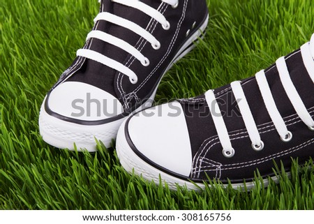 Sneakers on the green grass, youth shoes, field of green grass, shoes for young people, a pair of black sneakers, a new pair of sneakers, walking in black gym shoes on a green grass, shoes closeup