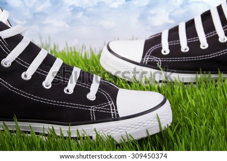 Couple youth sneakers, black and white sneakers, shoes on the green grass, outing, footwear close-up, green lawn, against the sky shoes, shoes for youth, sports shoes on the green grass.