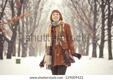 Beautiful red hair girl in winter park with snow