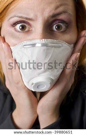 Woman wears a face mask and medical scrubs with a wide-eyed expression of concern or fear