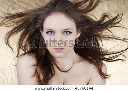 Beautiful woman with long hair in motion created by wind over white background