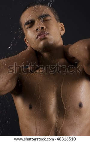 Drops of the water on naked body of a young man on black background.