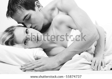 Loving affectionate nude heterosexual couple on bed in affectionate sensual kiss.