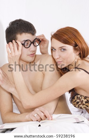 A girl trying to get some attention from her shocked boyfriend, who\'s busy reading a book.