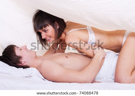 Young sexy couple making love in bed under the blanket