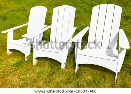 White Adirondack chairs on the grass.  Outdoor furniture painted white.