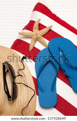 Flip flops, hat, towel, sunglasses and earphones for a day at the beach, spa or pool. Red, white and blue theme. Vertical format. Top view, looking down.