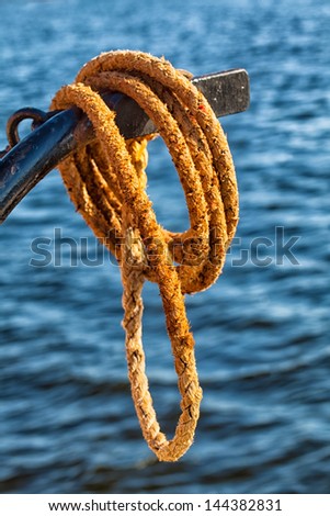 Nautical rope detail in a close up image with water in the background