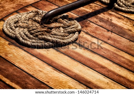 Detail of nautical braided rope on a wooden ship deck. Vintage color palette. Copy space.