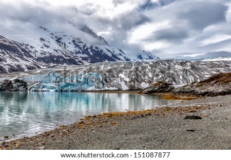 Alaska glacier landscape with reflections in a blue lake of melted glacial water. Location: Reid Glacier at Glacier Bay National Park