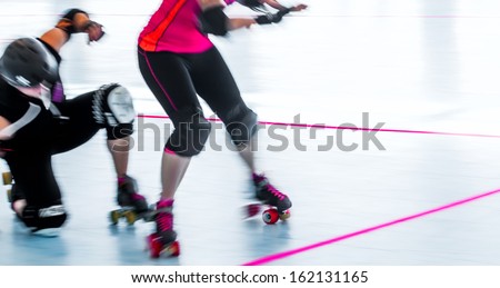 Panning action shot with motion blur of skaters in a roller derby, one falling down. Copy space.
