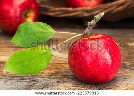 Shiny red apple with stem and green leaves on rustic wood. Concepts: farm to table, healthy choice, dessert, school lunches