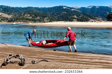 BOLINAS, CA-OCT 2, 2013: Active senior couple lifting a kayak into the water. Physical activities help seniors maintain fitness, health and independence.