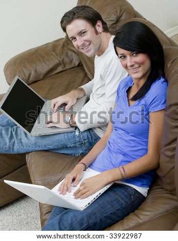 A young couple working on their computers while relaxing at home