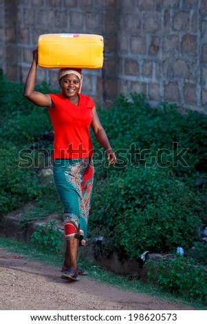 ACCRA, GHANA - MARCH 18: Unidentified African woman carry thing on her head on March 18, 2014 in Accra, Ghana. Carrying things on head is general skill of African girls and women.