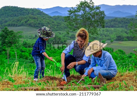 Asian family planting tree in farm near mountain