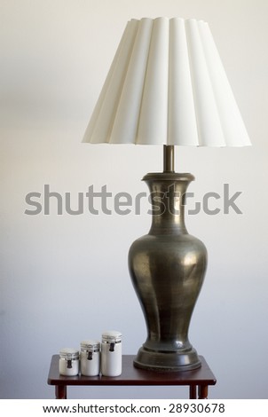 Still life of a large table lamp and matching porcelain containers on a small table.