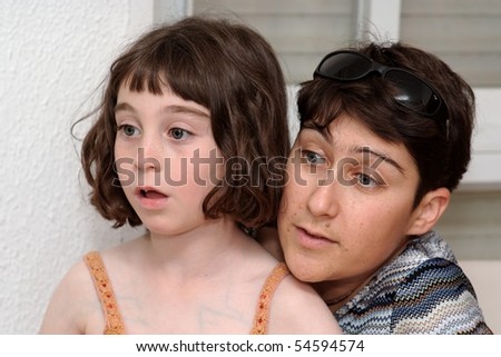 Mother and cute little daughter watch TV in great concentration