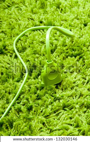 Plug in earth. Green electric plug on the green carpet.