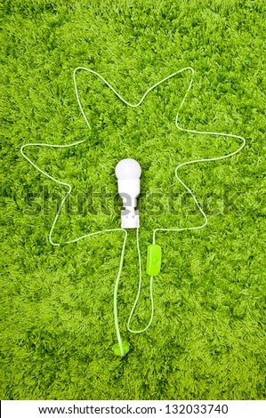 Wire flower plugged  to the earth. Energy saving lamp in the socket, with green wire, on the green carpet.