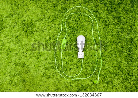 Energy saving lamp in the socket, with green wire, on the green carpet.