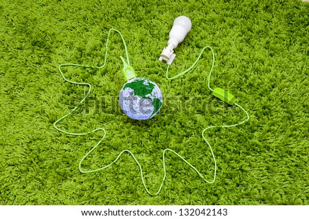 Pumping energy from the world. Made of threads ball connected with lamp in the holder, by green wire, on the green carpet.