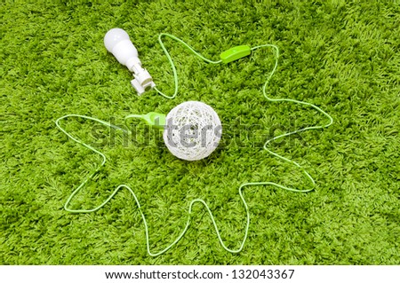 Energy balls. Made of threads ball connected with lamp in the holder, by green wire, on the green carpet.