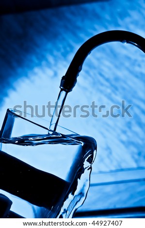 The woman pours water from the crane in a glass