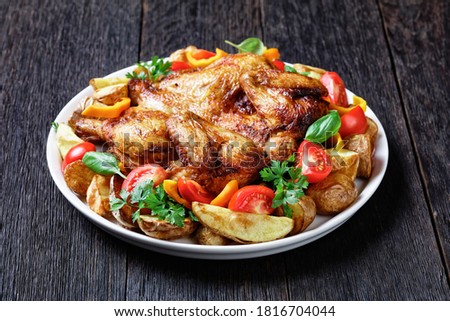 roast chicken served  with roasted potato, fresh tomatoes, peppers and herbs on a white platter on a rustic wooden table, horizontal view from above, close-up ストックフォト © 