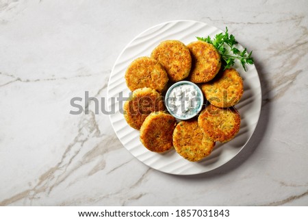 Fish cakes of cod or haddock fillet with potato and parsley, breaded in breadcrumbs on a white plate with tartar sauce in a gravy boat on a light marble stone background,  top view, close-up Stockfoto © 
