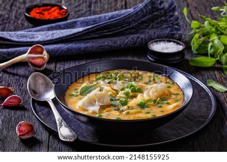 delicious fish chowder with cod, green peas, potatoes and plant based milk sprinkled with fresh sage, thyme in a black bowl on dark wooden table, horizontal view from above Foto stock © 