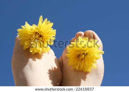 Toes in sunlight holding flowers.