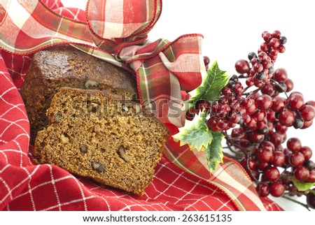 Delicious Christmas banana nut bread with colorful red ribbon and berries for decoration, on a horizontal white background and focus on bread