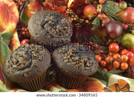 Three Chocolate Chip Chocolate Muffins on fall placemate with colorful fall decorations, horizontal