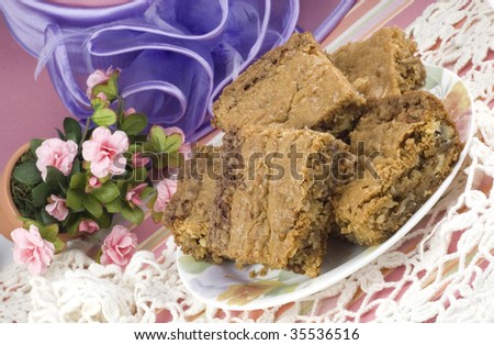A plate of delicious fresh baked coconut pecan blondies with a feminine presentation, perfect for mother's day, selective focus