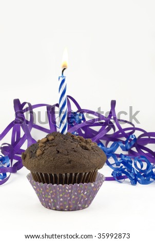 Chocolate birthday muffin with one burning candle, decorated with purple and blue  curly ribbons, isolated on white vertical background with copy space