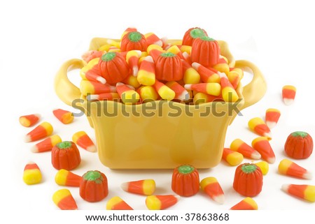 A yellow dish filled with Halloween candy corn and candy pumpkins, isolated on white background with copy space