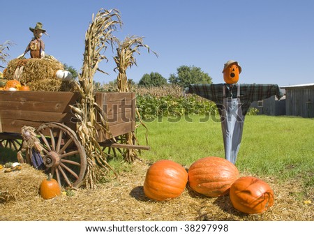 Scarecrows on a pumpkin farm with a wagon of hay, fall decorations, blue sky, horizontal with copy space