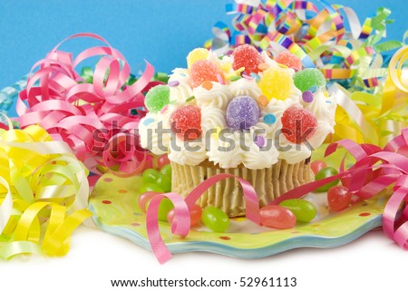 A colorful party cupcake with bright colored party decorations, horizontal with copy space, selective focus