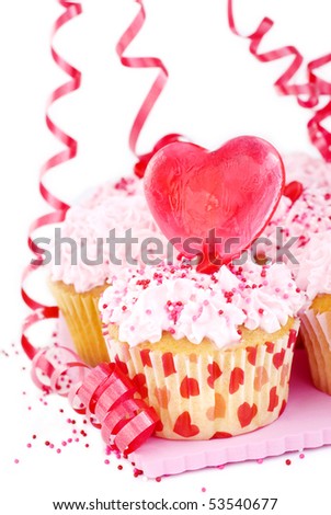 Valentine\'s cupcakes with sprinkles and a heart shaped candy heart and ribbon streamers