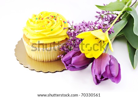 A delicious yellow cupcake with spring tulips and lilac on a white background with copy space