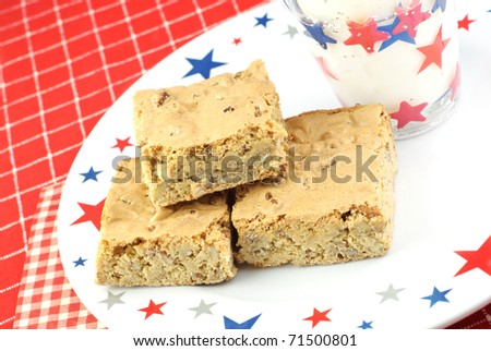 A patriotic plate with Pecan Caramel Chewy Holiday Bars with a glass of milk, copy space