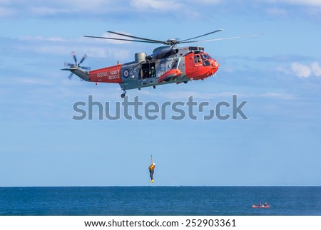 DAWLISH, UNITED KINGDOM - AUGUST 23, 2014: Royal Navy Sea King Search and Rescue Helicopter Demonstrating Winch Rescue at the Dawlish Airshow