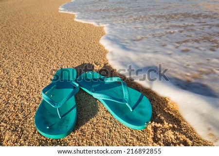 pair of sandals just about to be washed away by the sea on the beach