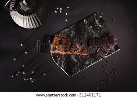 Chocolate cake on a black marble cake with a black tea pot