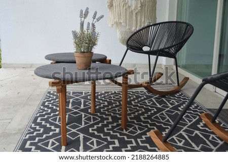 outdoor terrace with outdoor coffee tables, stone top and solid wood or hardwood base, design mat at the bottom, al fondo pasto y vegetaci n de jard n grass and garden vegetation at the back. Foto stock © 