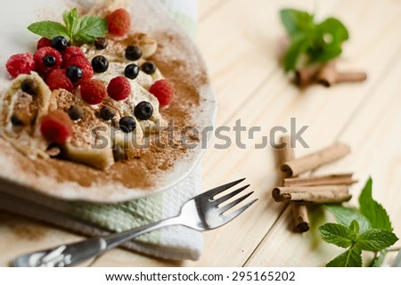 A plate of homemade sweet fresh cottage cheese filled dumpling roll, garnished with berries, powdered cinnamon and mint. Traditional Slovenian cuisine. On a wooden table.